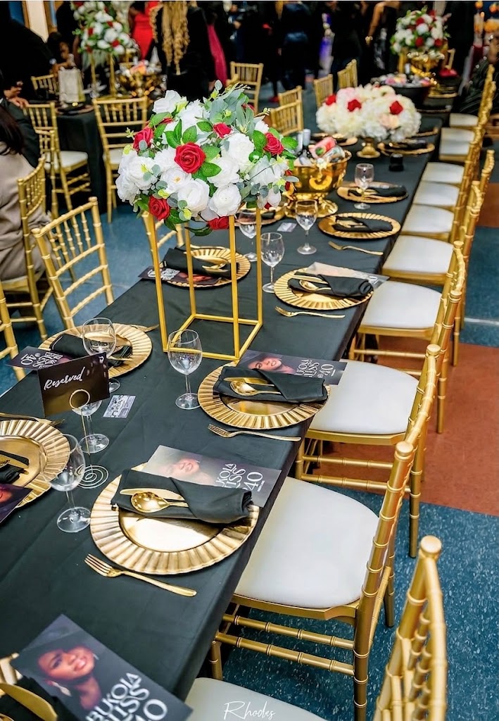 Black and gold tablescape with red and white floral centerpieces, gold chiavari chairs, and gold charger plates