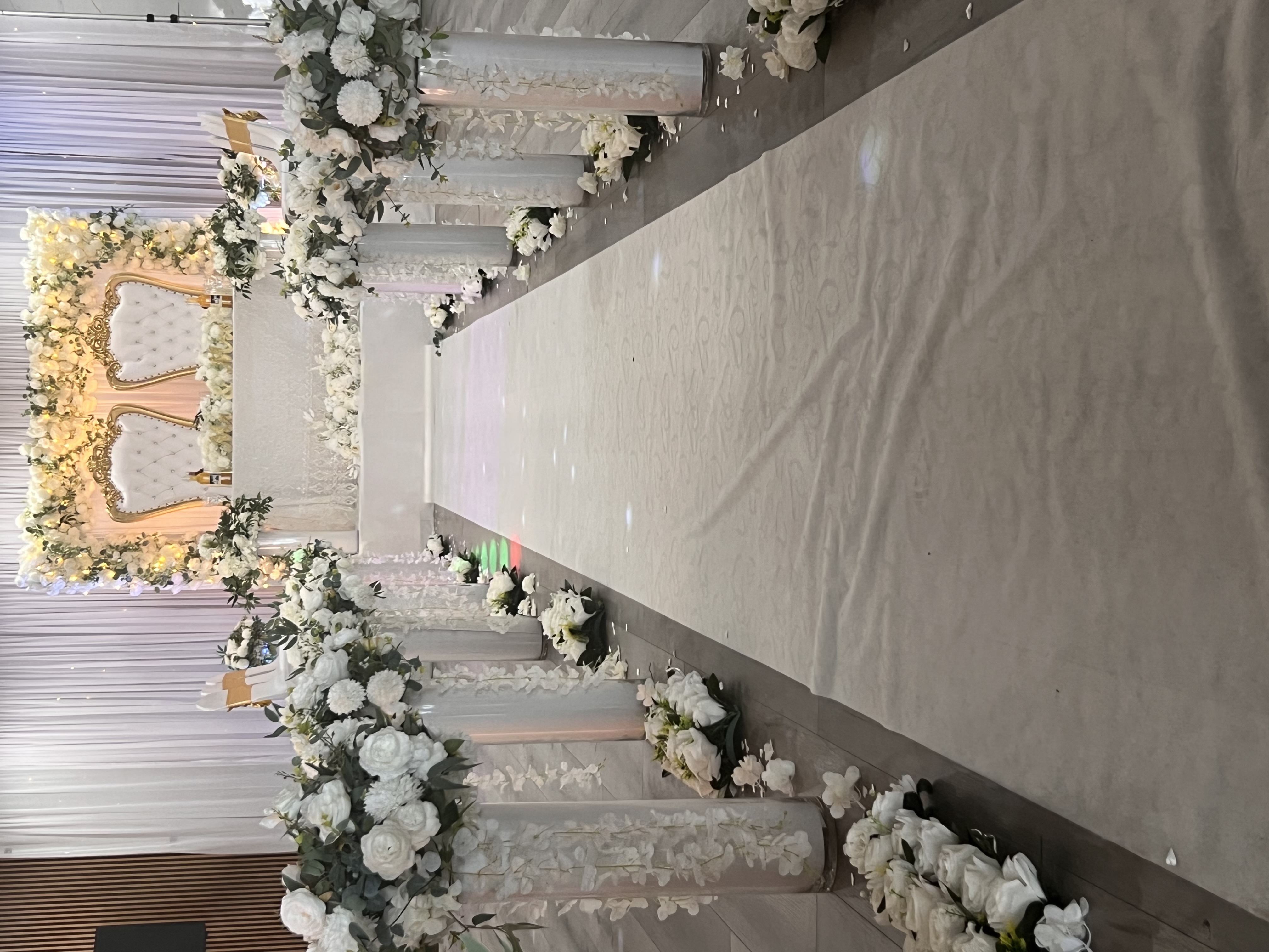 White and gold ceremony aisle with floral pillar arrangements and a throne backdrop